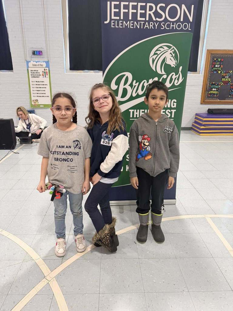 A group of students smiling in front of a green and blue sign, 