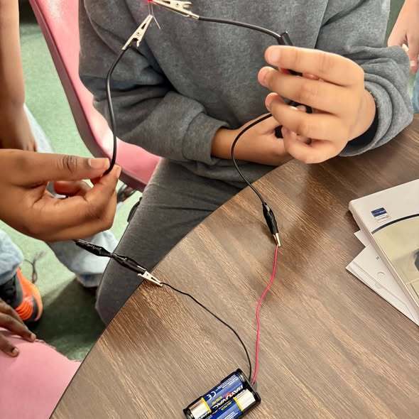 Two hands holding wires together.