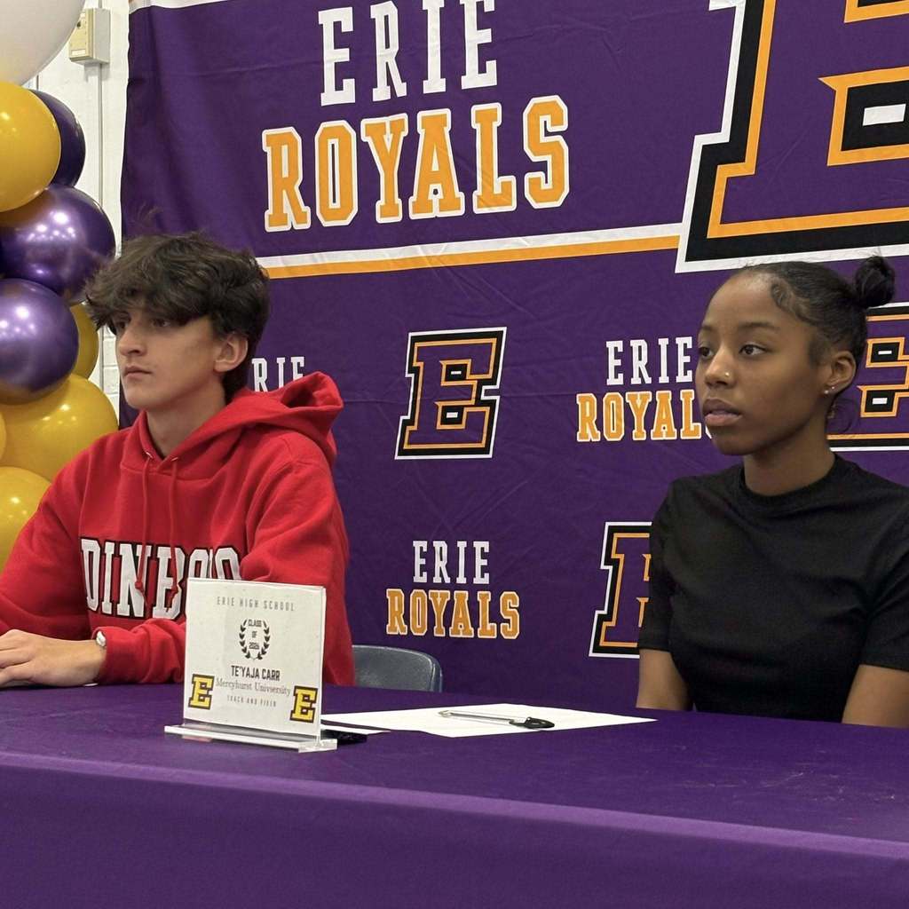 A boy and girl sitting behind a purple table.
