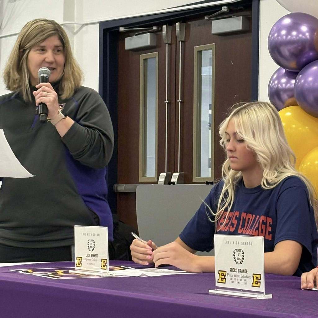 A women speaking into a microphone next to a girl sitting at a table.