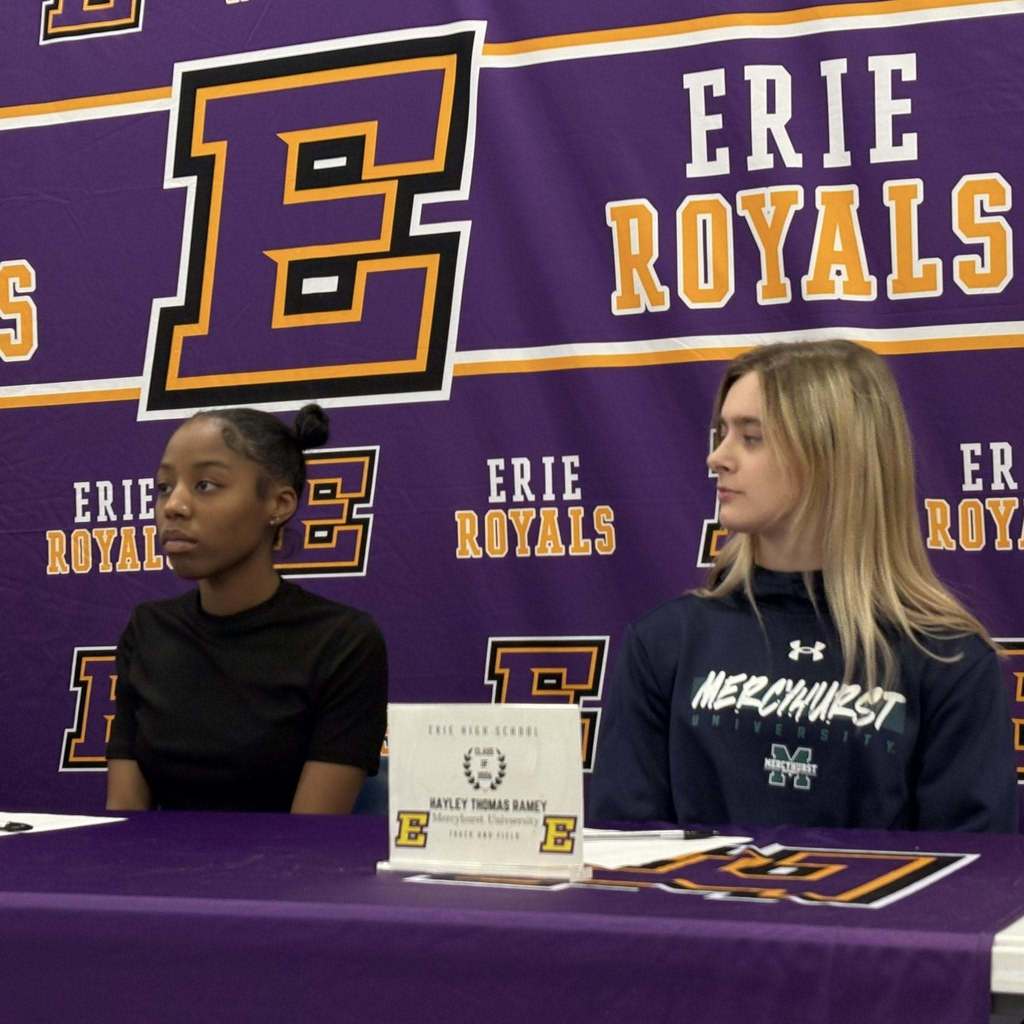 Two girls sitting behind a purple table.