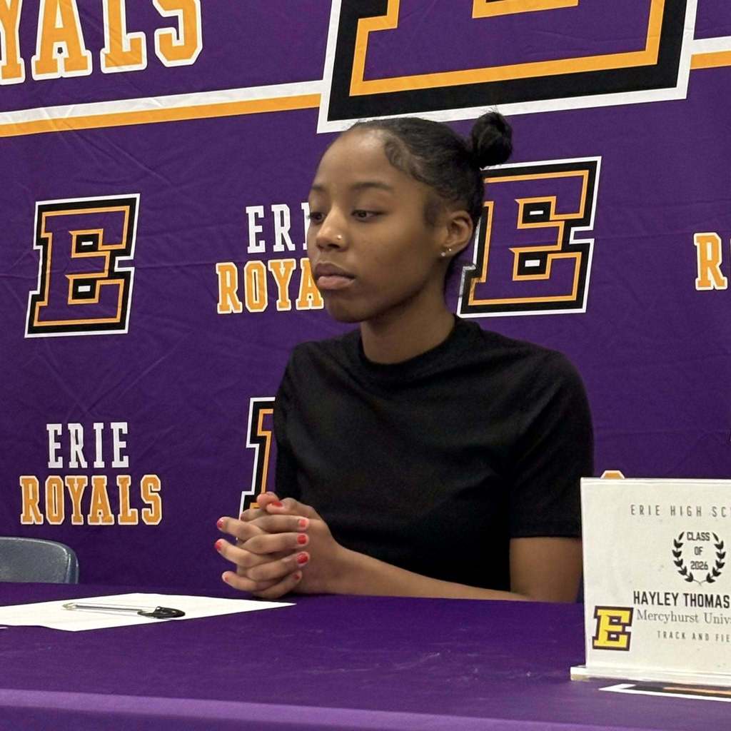 A young girl in a black shirt sitting behind a purple table.