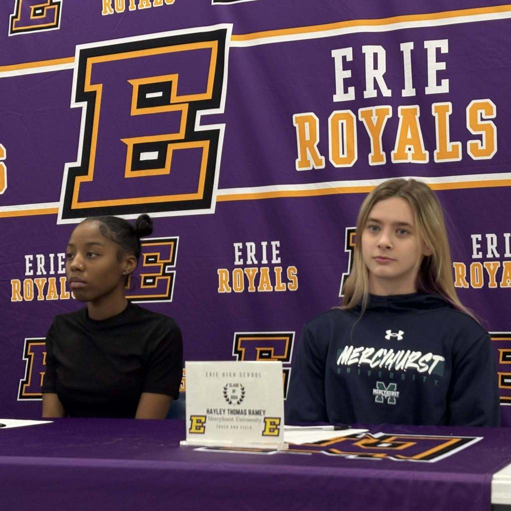 Two girls sitting behind a purple table.