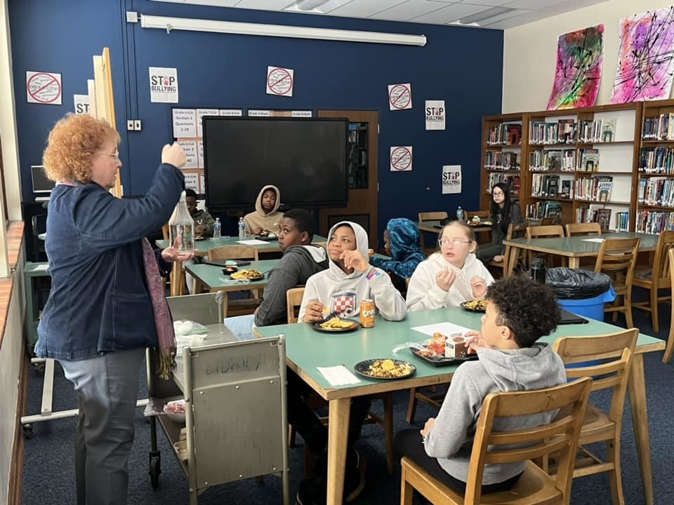 Kids sitting in a classroom while an adult talks. 
