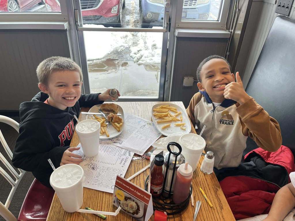 Kids sitting and eating in a booth of a restaurant and smiling.
