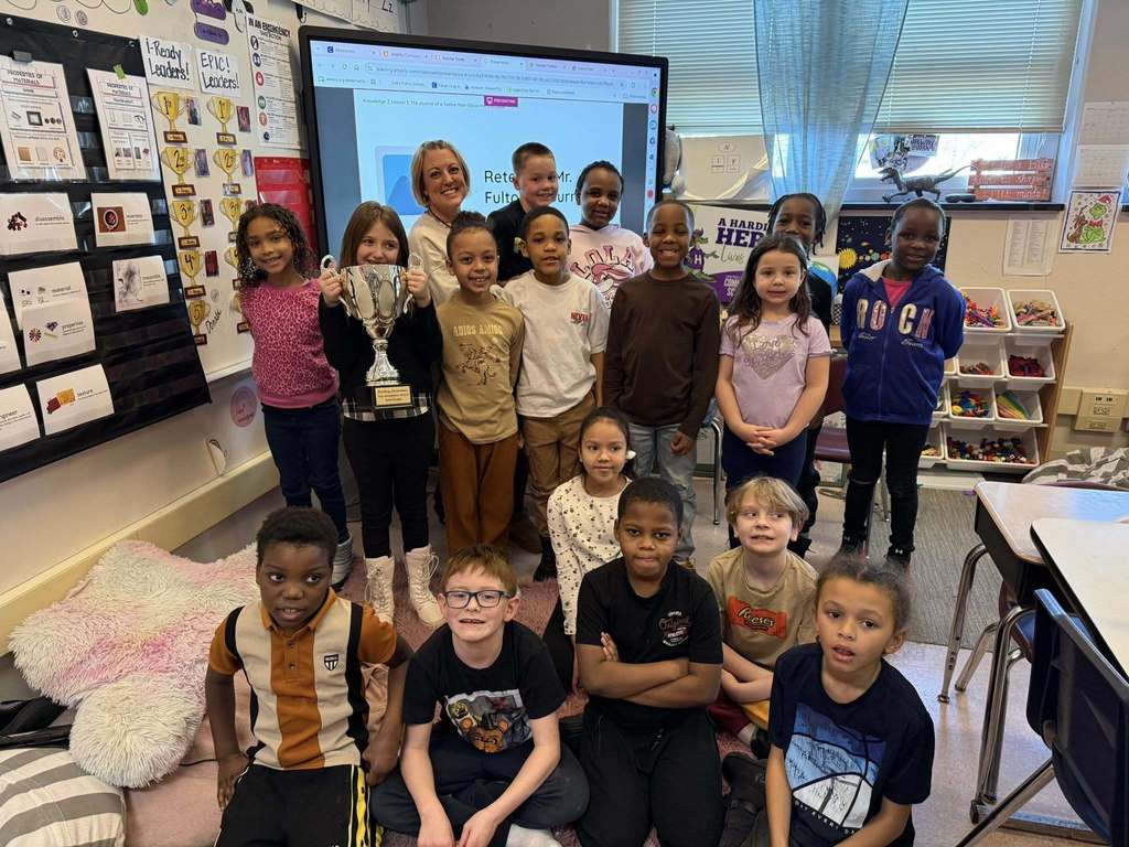 A group of students and an adult in a classroom.