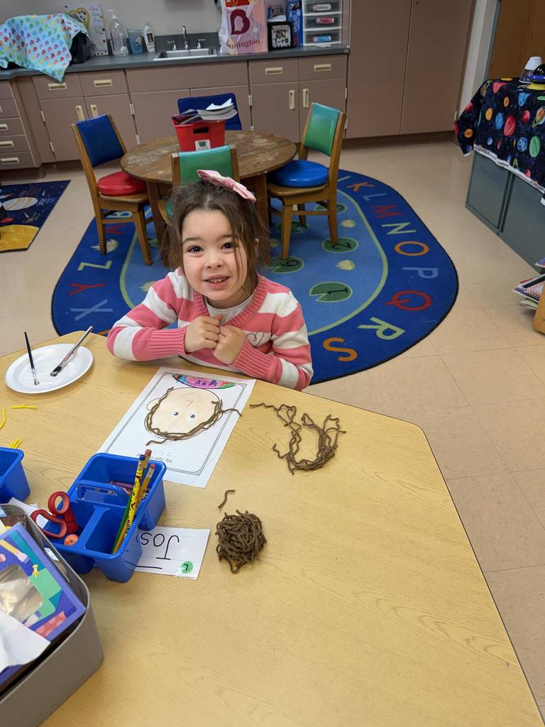 Young girl making art in a classroom.