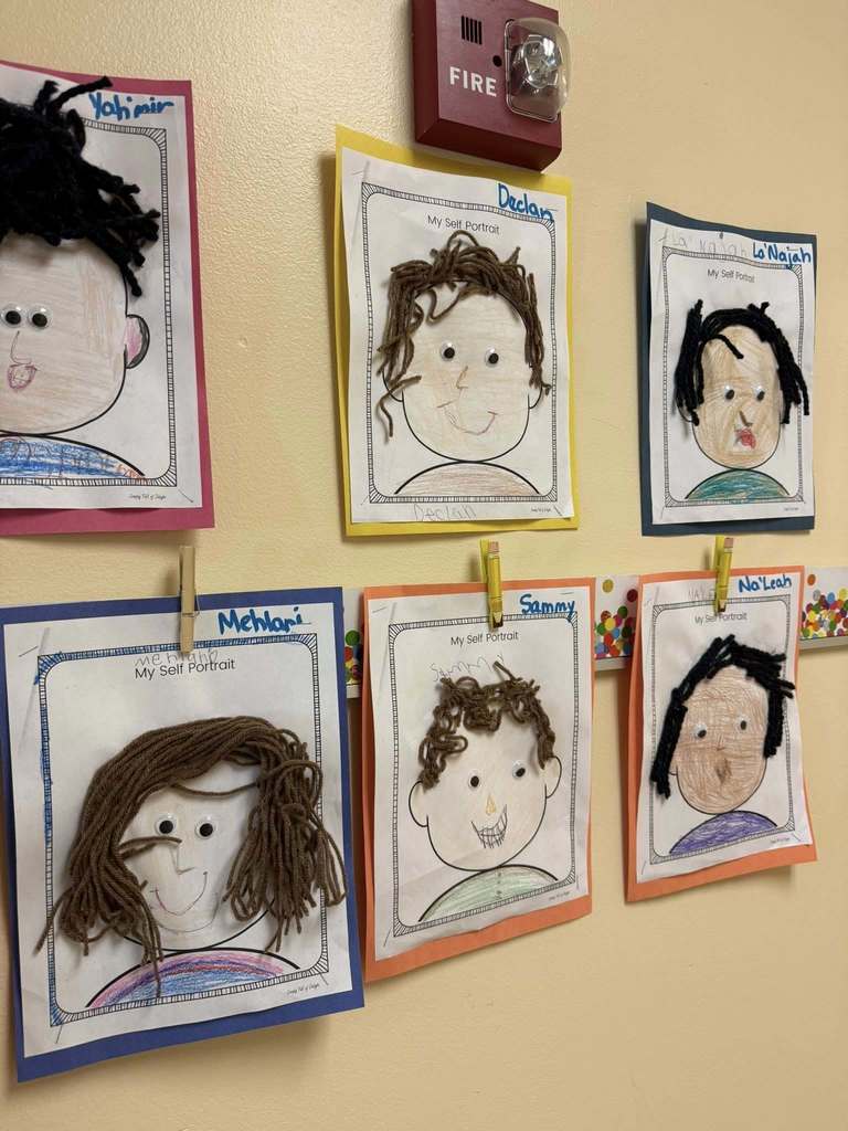 Drawings displayed on a wall with hair made from string.