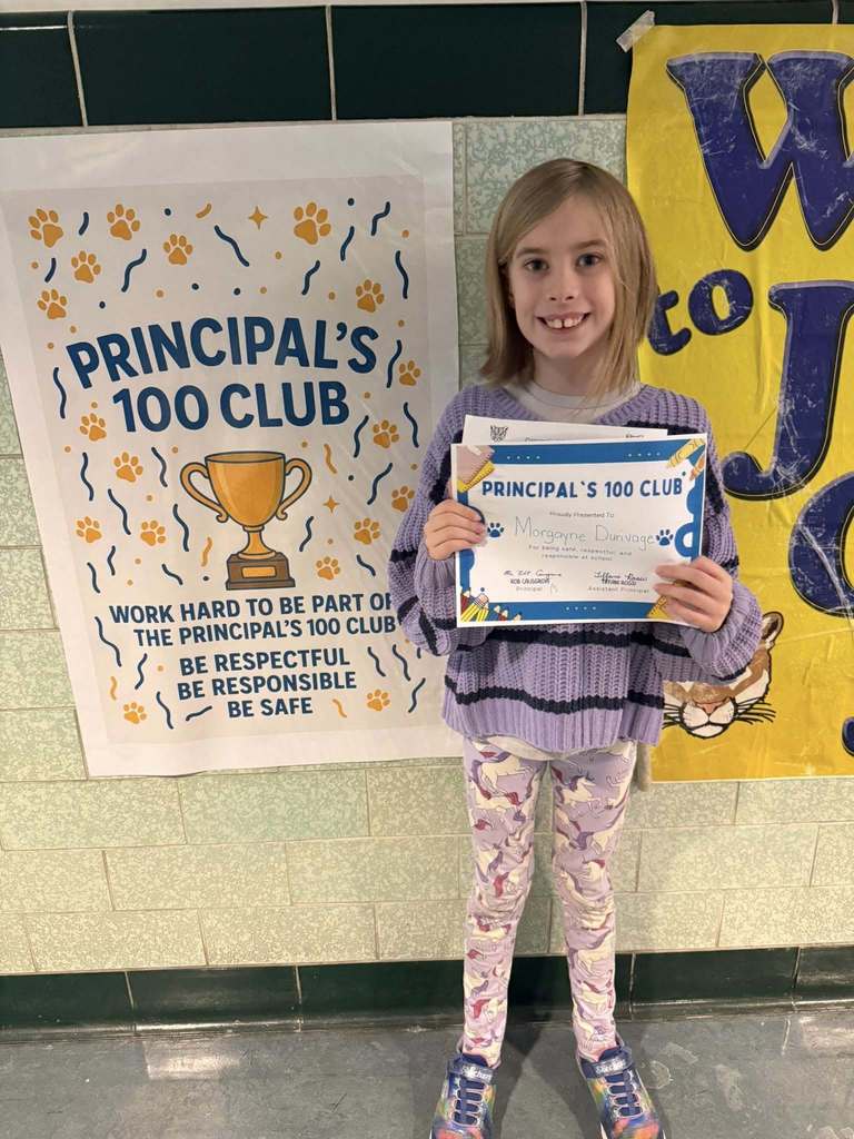 A young girl in a purple outfit holding up his certificate.