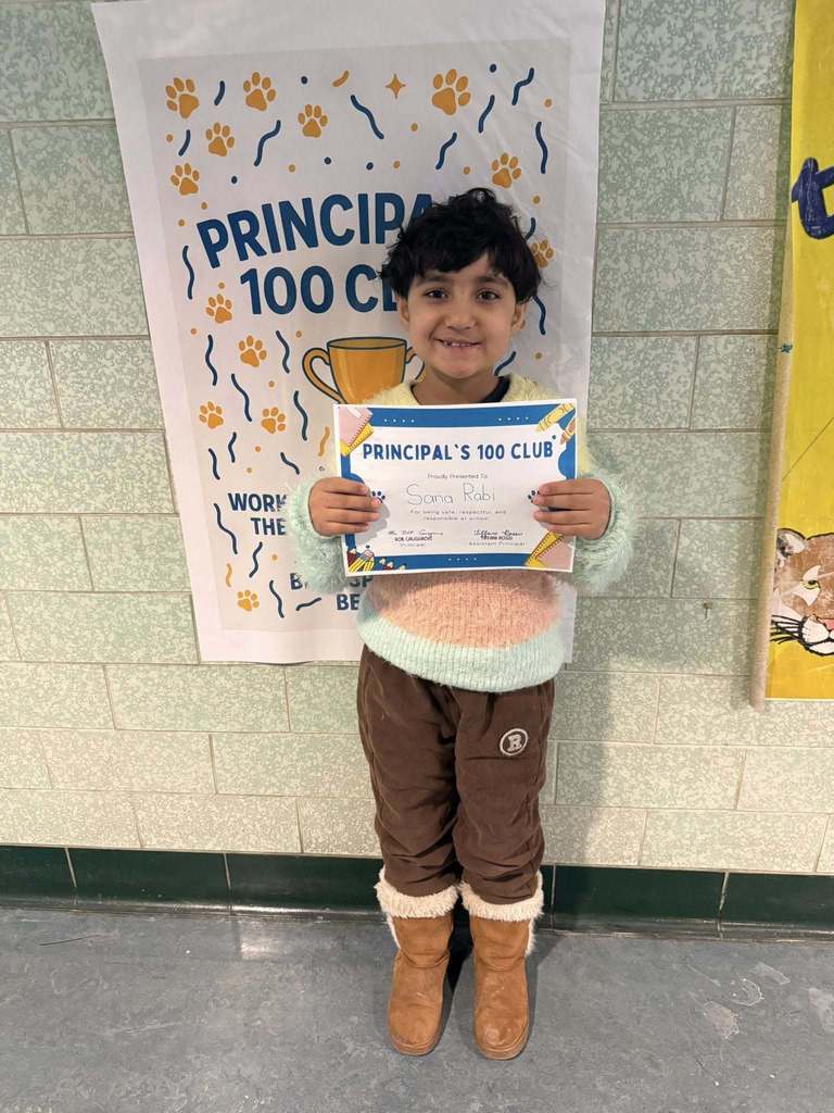 A young child in a colorful top holding up his certificate.