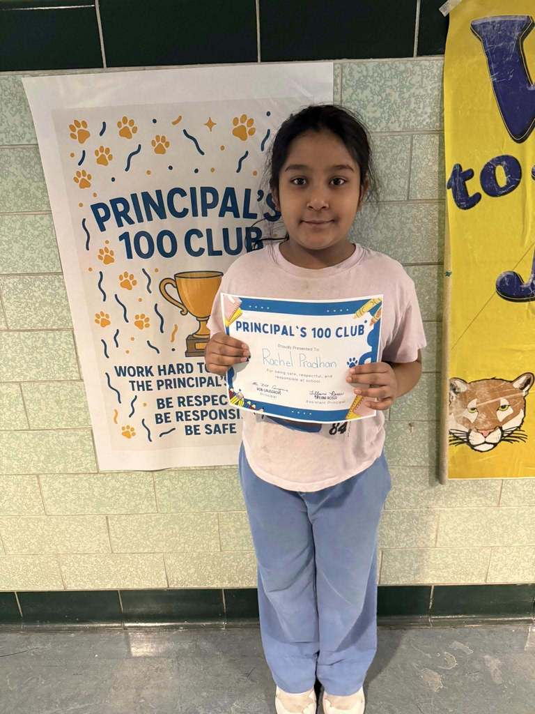 A young girl in a pink shirt holding up his certificate.