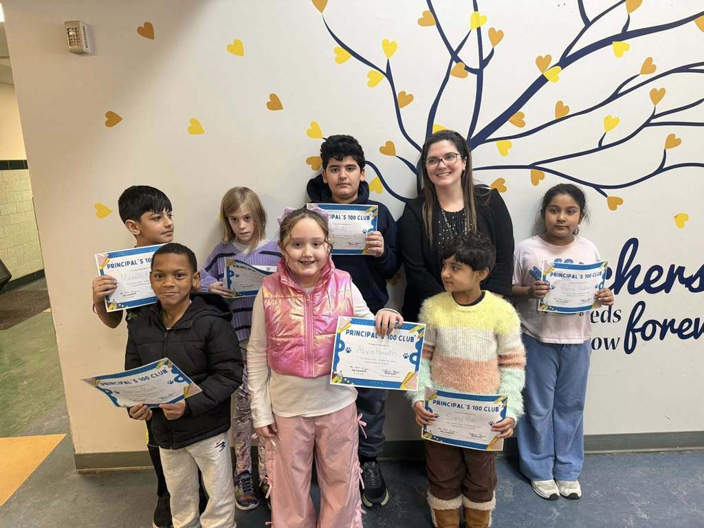 Group of students and an adult standing in a hall while the students hold their certificates.
