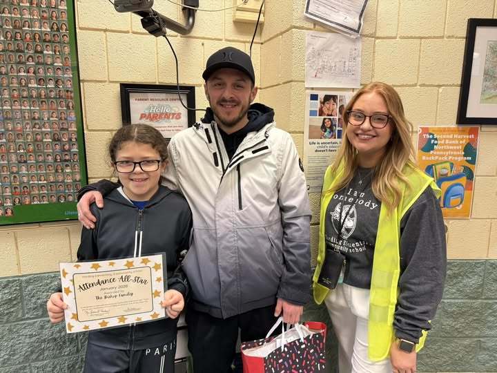 A photo a a kid holding a certificate next to a man and women.