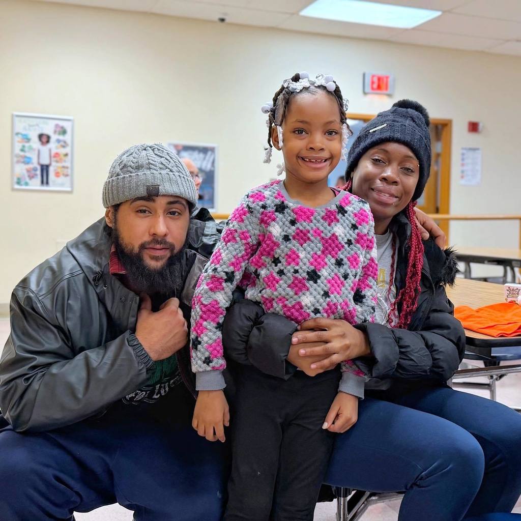 A kid smiling with her parents. 