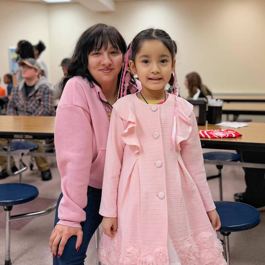 A young girl smiling with her mom. 