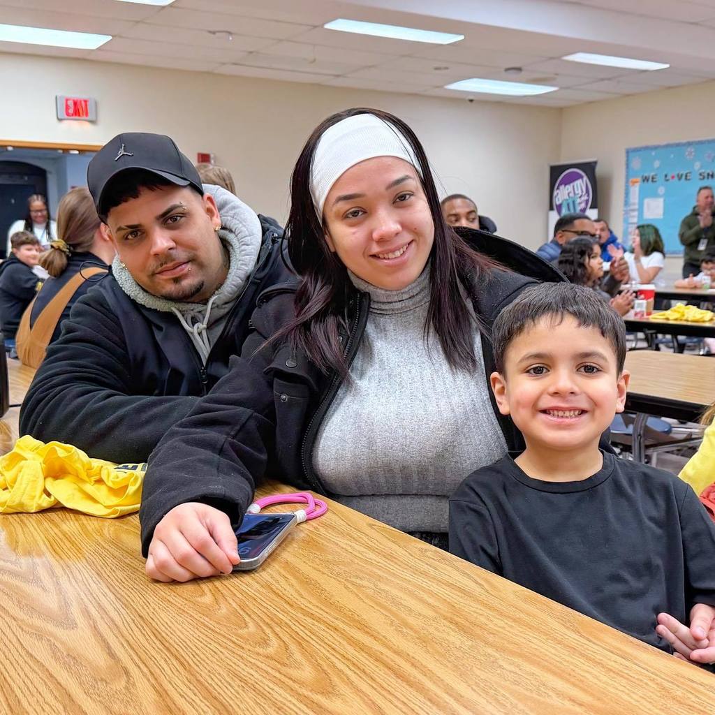 A kid smiling with his parents. 