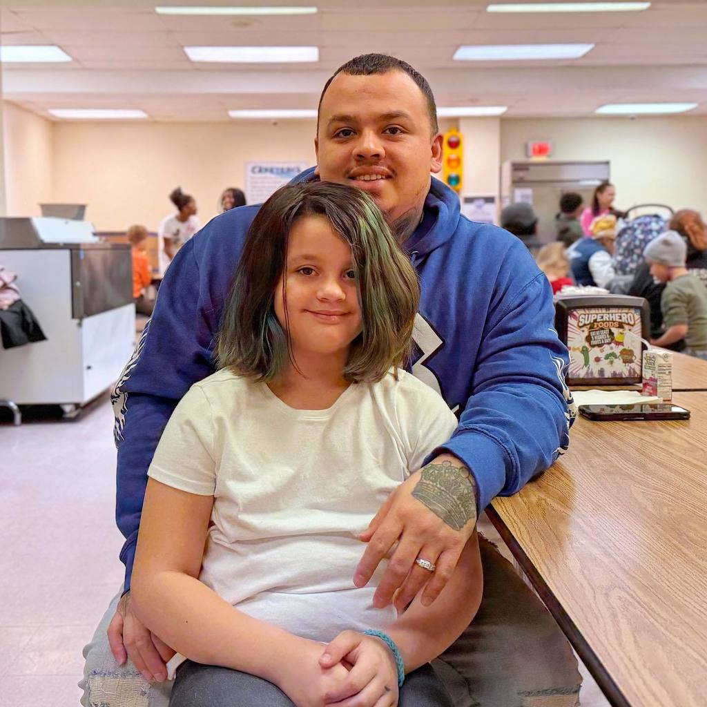 A young girl sitting in front of a man and they are both smiling. 