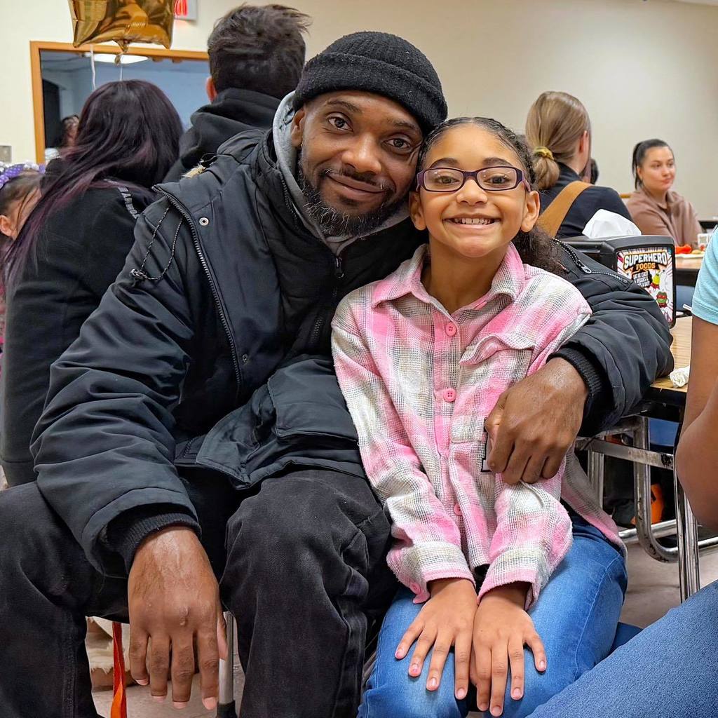 A young girl smiling with her dad. 