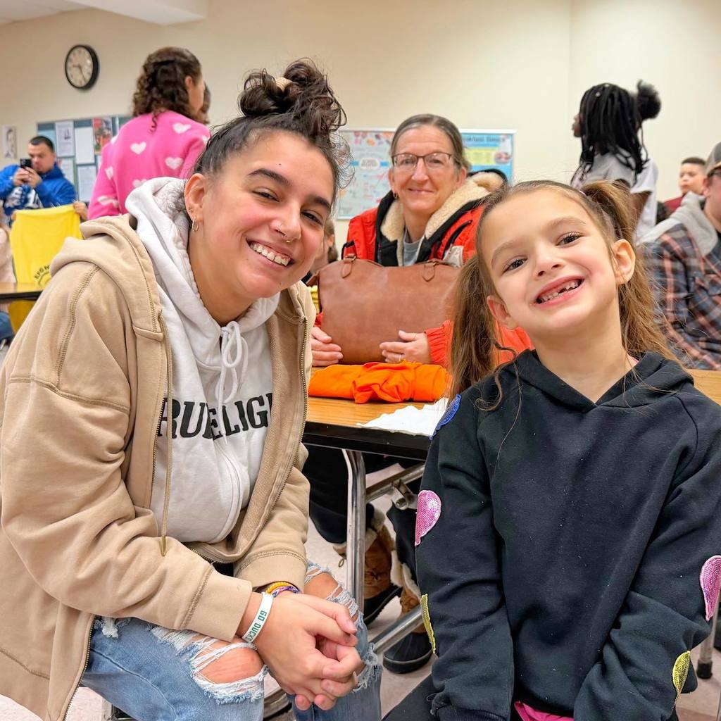 A young girl smiling with her mom. 