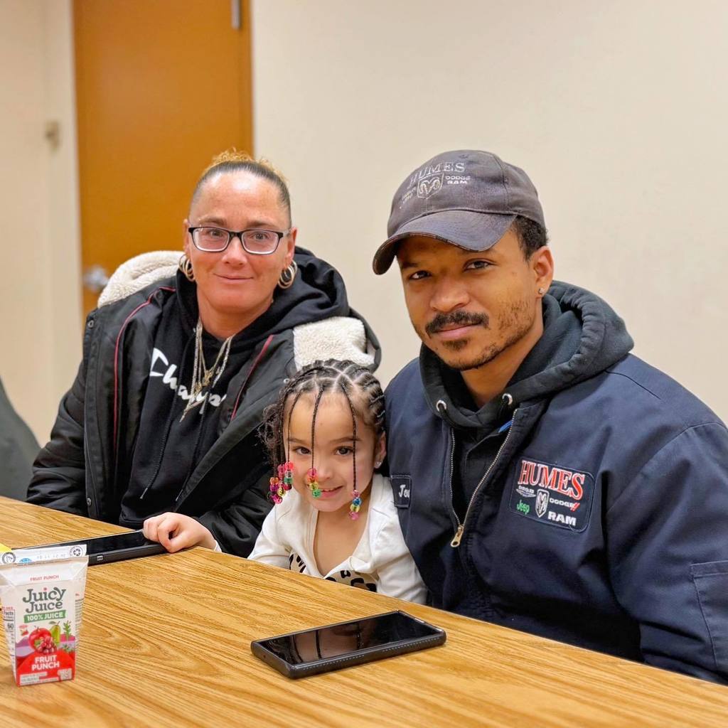 A kid smiling with her parents. 