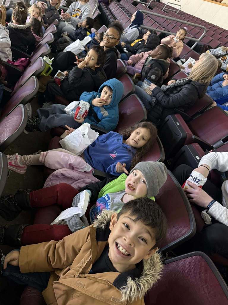 Kids sitting in an arena.