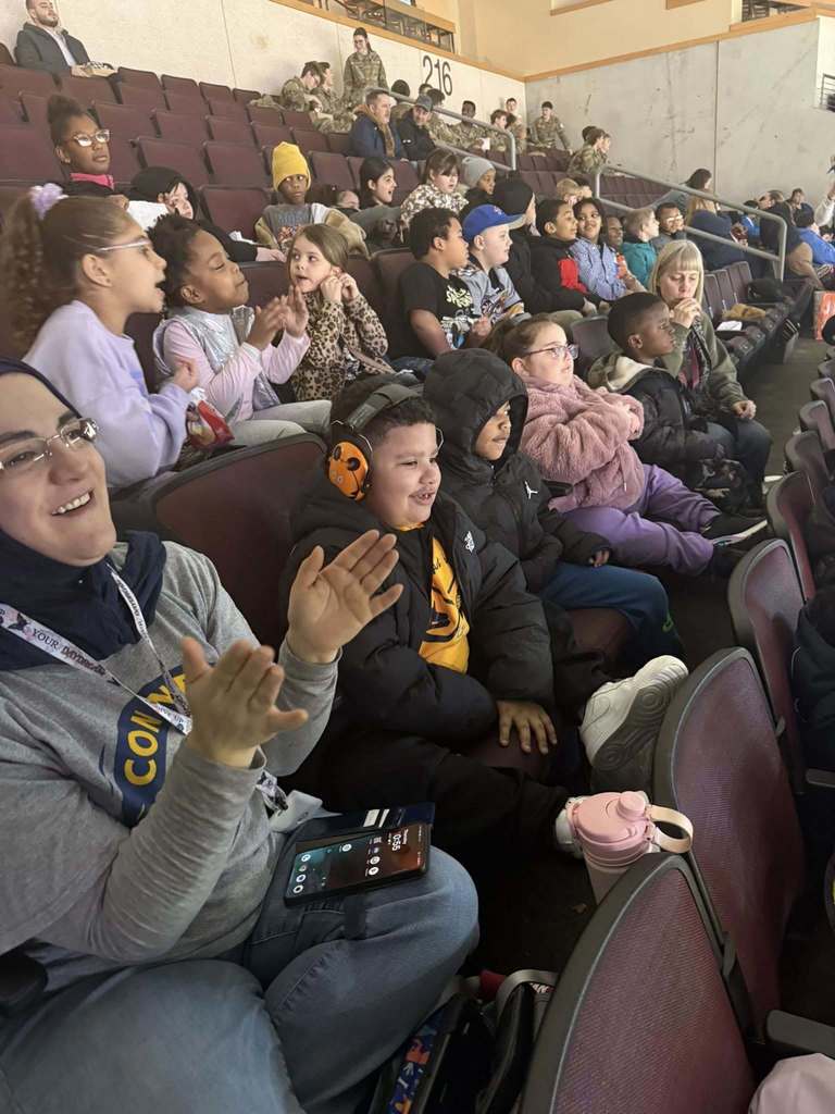 Kids and adults sitting in an arena.