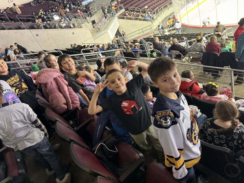 Kids and adults standing in an arena.