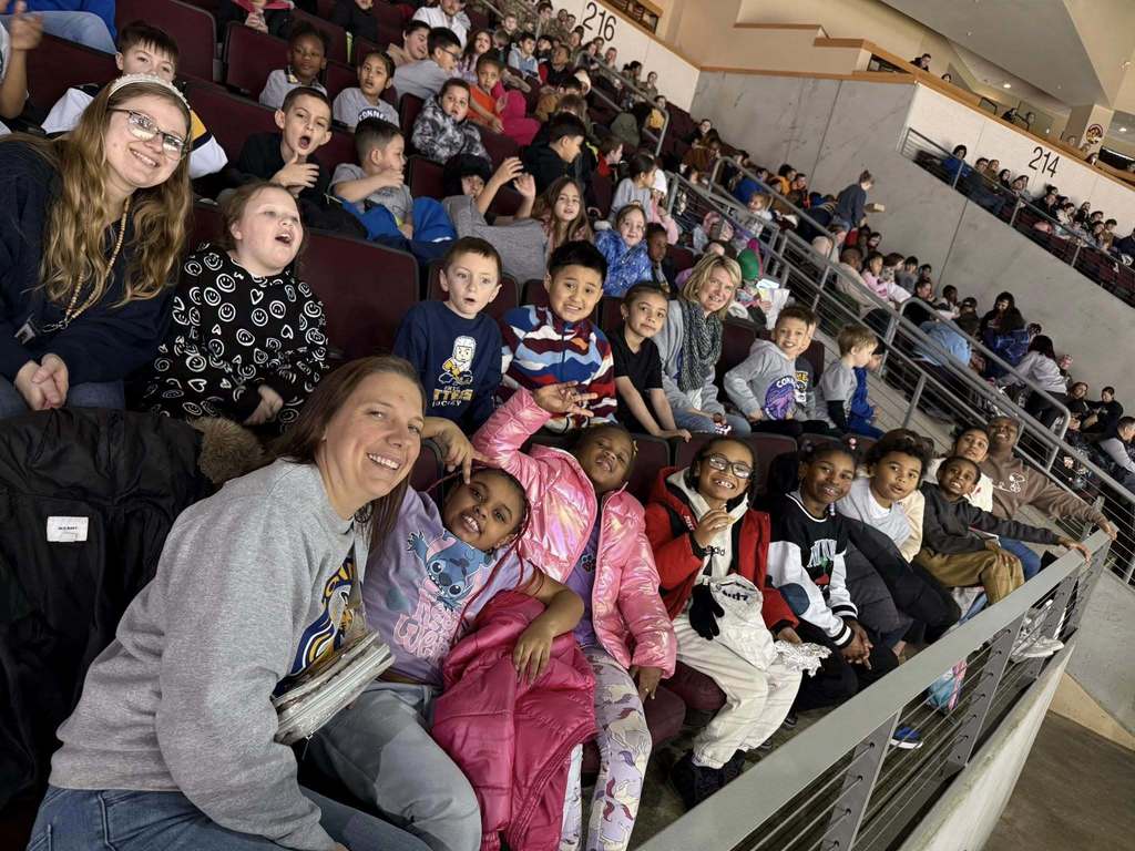 Kids and adults sitting in an arena.