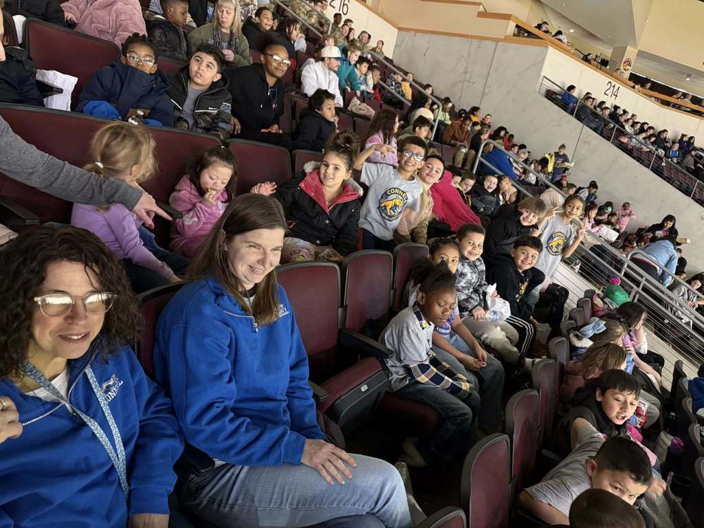 Kids and adults sitting in an arena.