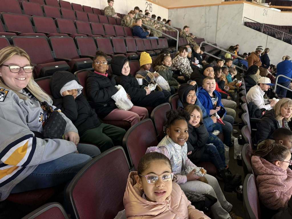 Kids and adults sitting in an arena.