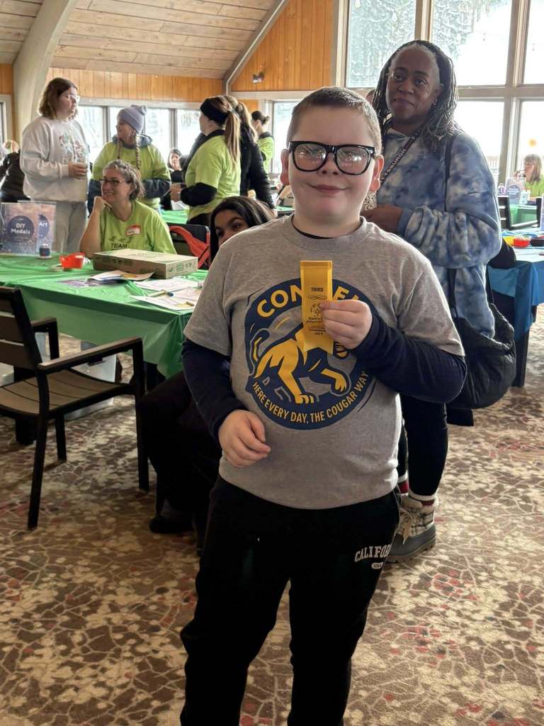 Young boy in a gray shirt holding his yellow ribbon. 