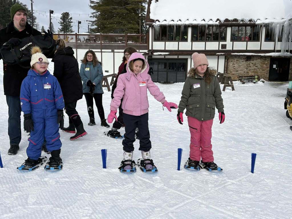 Kids in winter gear outside in the snow. 
