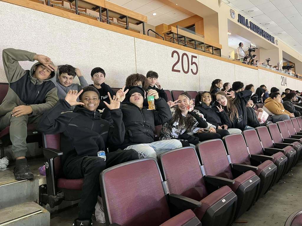 A group of kids sitting in an arena. 