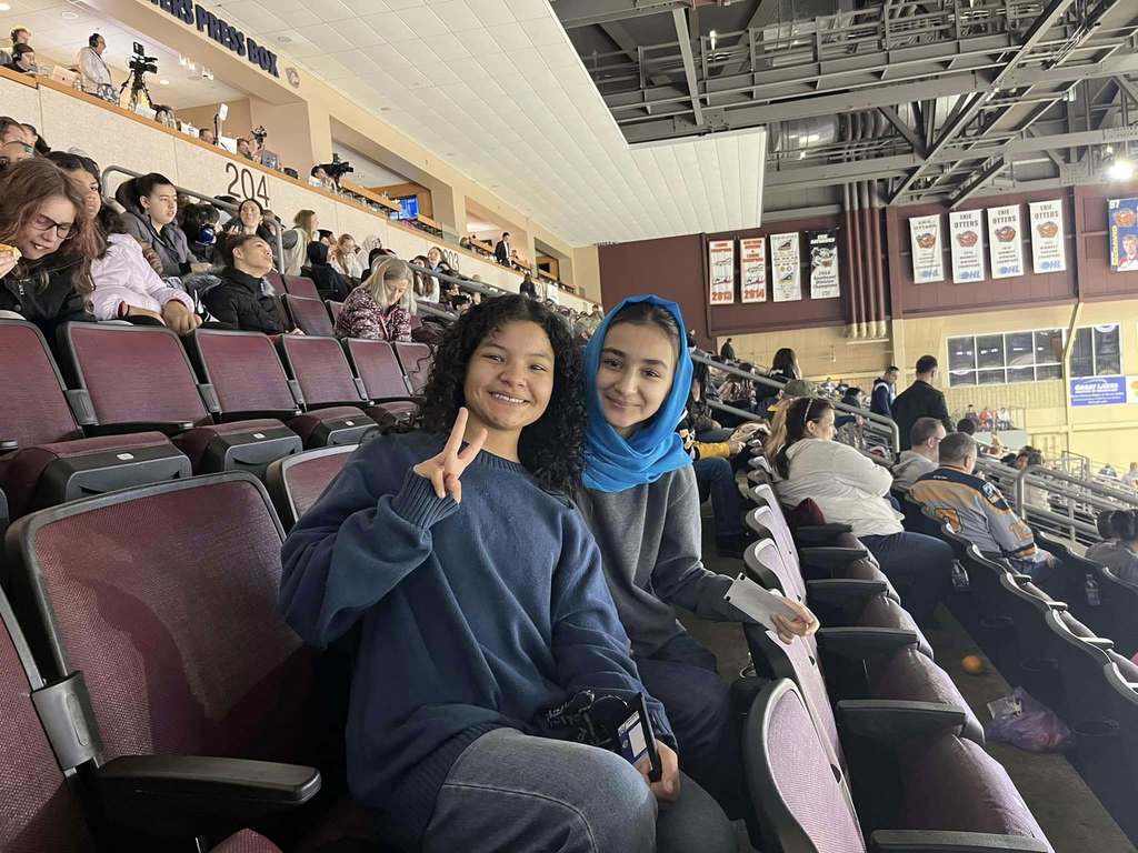 Two young girls sitting at an arena and smiling. 