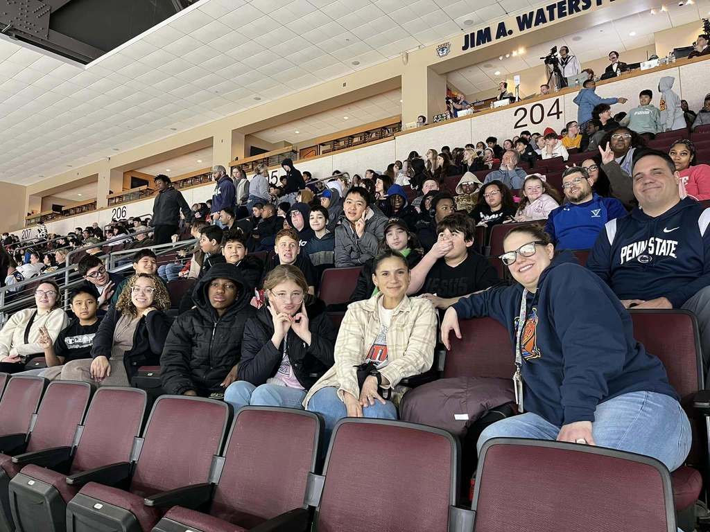A group of kids and adults sitting in an arena. 