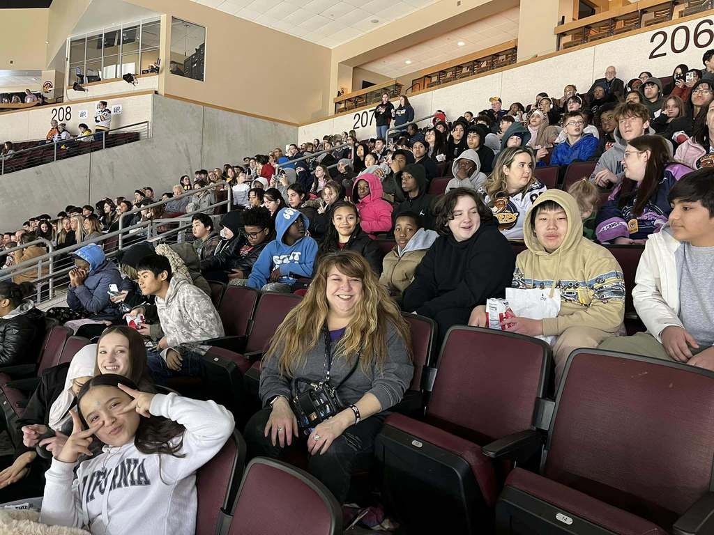 A group of kids and adults sitting in an arena. 