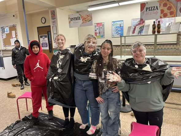 A group of individuals covered in shaving cream after they were pied in the face. 