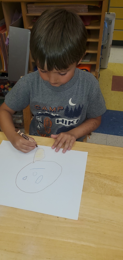 A little boy is drawing a picture of a person.