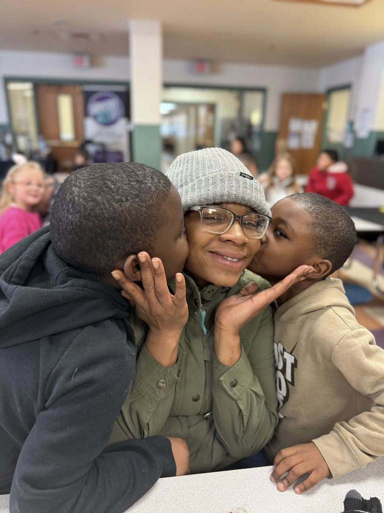 Two kids kissing their mom on the cheek.