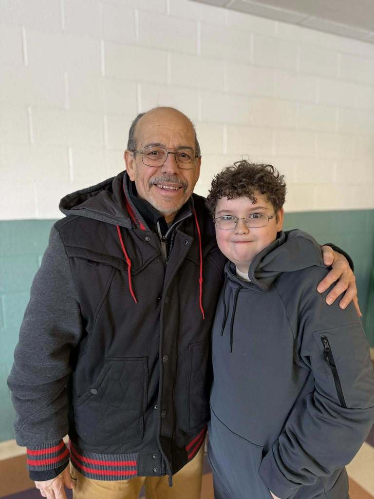 A young boy smiling with an adult.