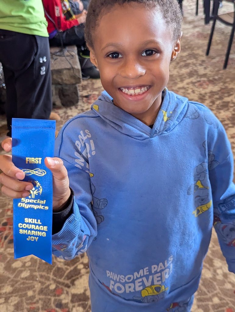 A young boy in a blue hoodie holding up his blue ribbon. 
