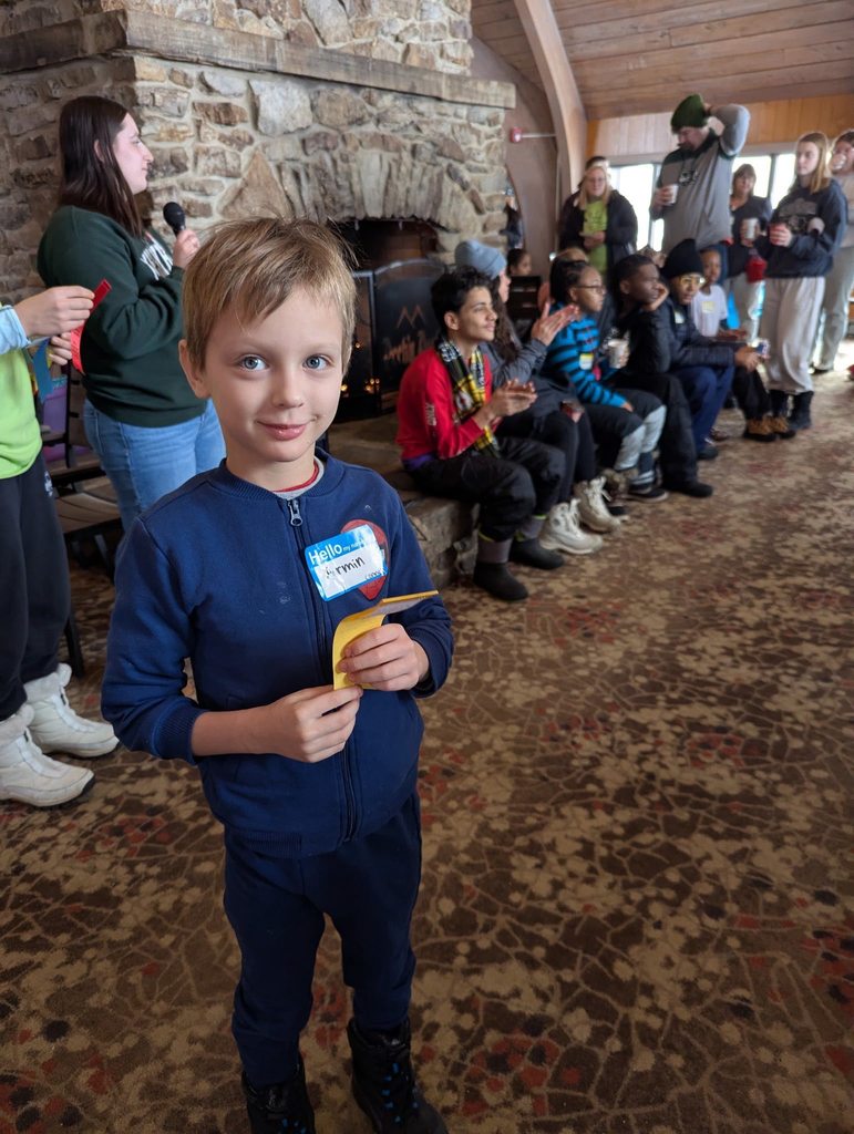 Young boy in a navy blue shirt and is holding a yellow ribbon. 