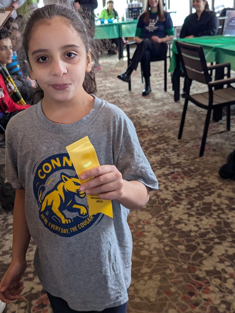 Young girl in a gray shirt is holding her yellow ribbon. 