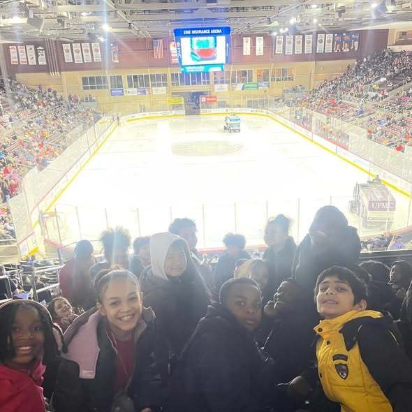 Kids sitting in a hocky arena. 