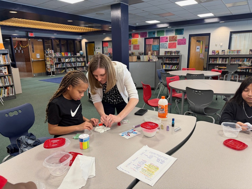 An adult helping a young girl make slime. 