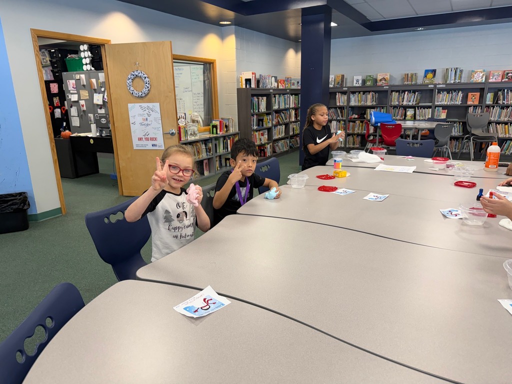 Kids playing with slime on a table in a library. 