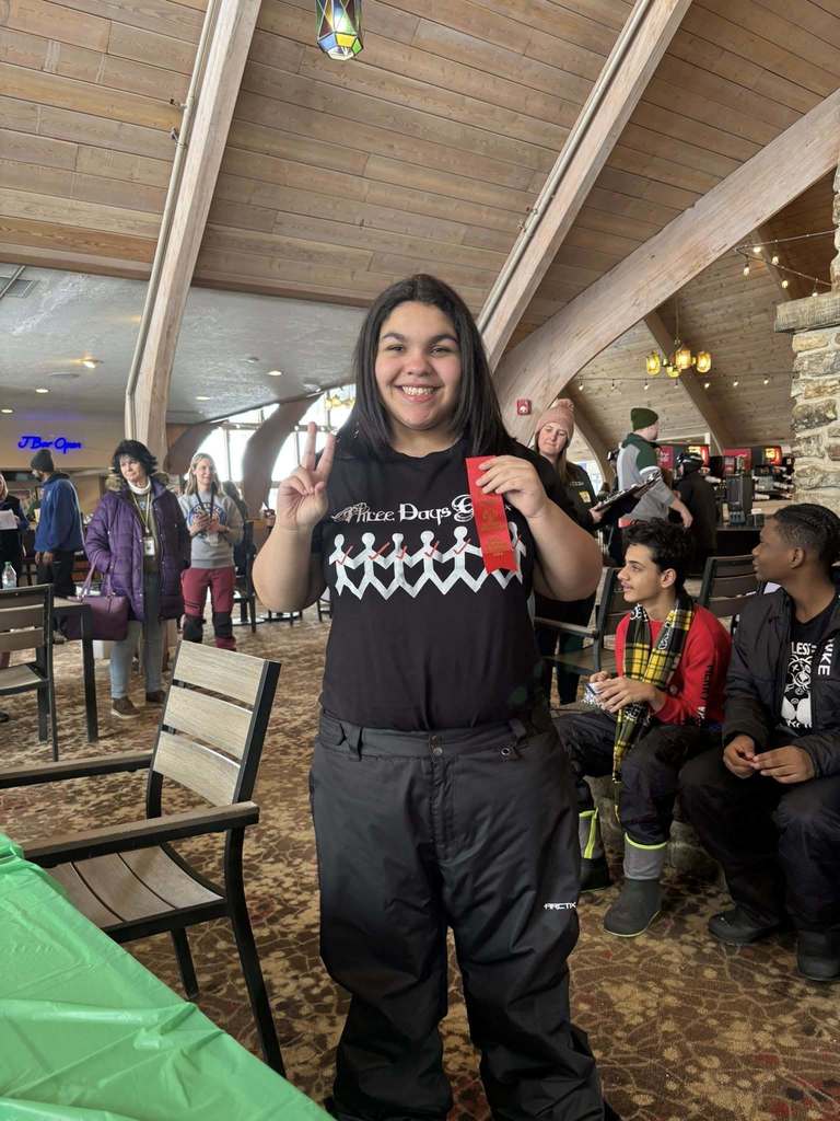 Young child in a black shirt is holding up her red ribbon. 