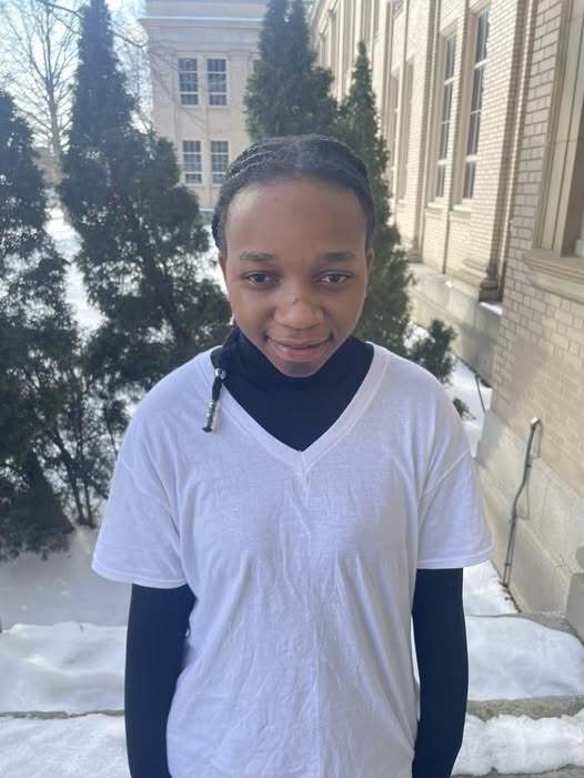 Young child in a white shirt smiling outside in the snow. 