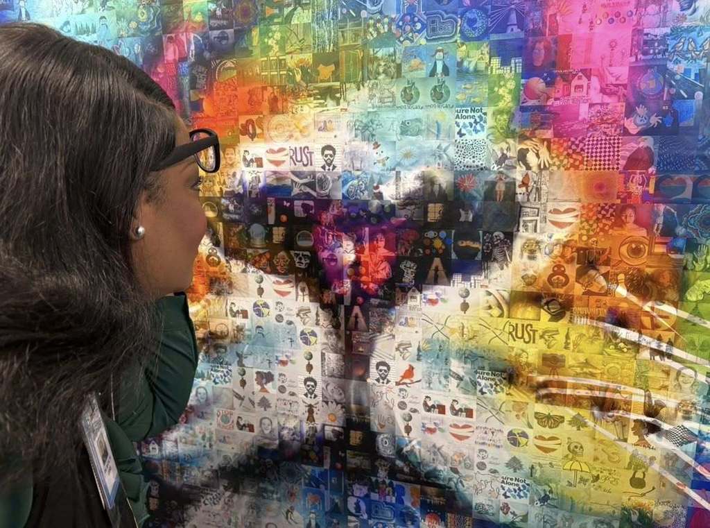 Woemn holding her glasses up and looking at artwork up close.