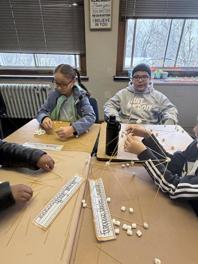 Students making something out of spaghetti and marshmallows. 